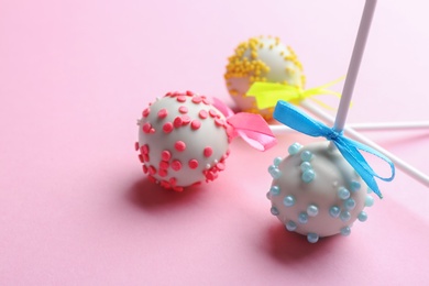 Photo of Different tasty cake pops on light pink background