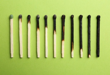 Row of burnt matches and whole one on color background, flat lay. Human life phases concept