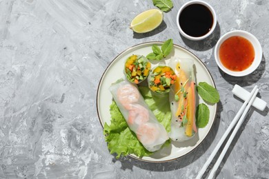 Photo of Tasty spring rolls served on grey textured table, flat lay. Space for text