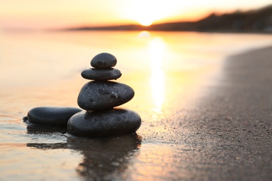 Photo of Dark stones on sand near sea at sunset, space for text. Zen concept