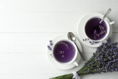 Fresh delicious tea with lavender and beautiful flowers on white wooden table, flat lay. Space for text