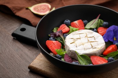 Photo of Delicious salad with brie cheese, blueberries and strawberries on wooden table, closeup