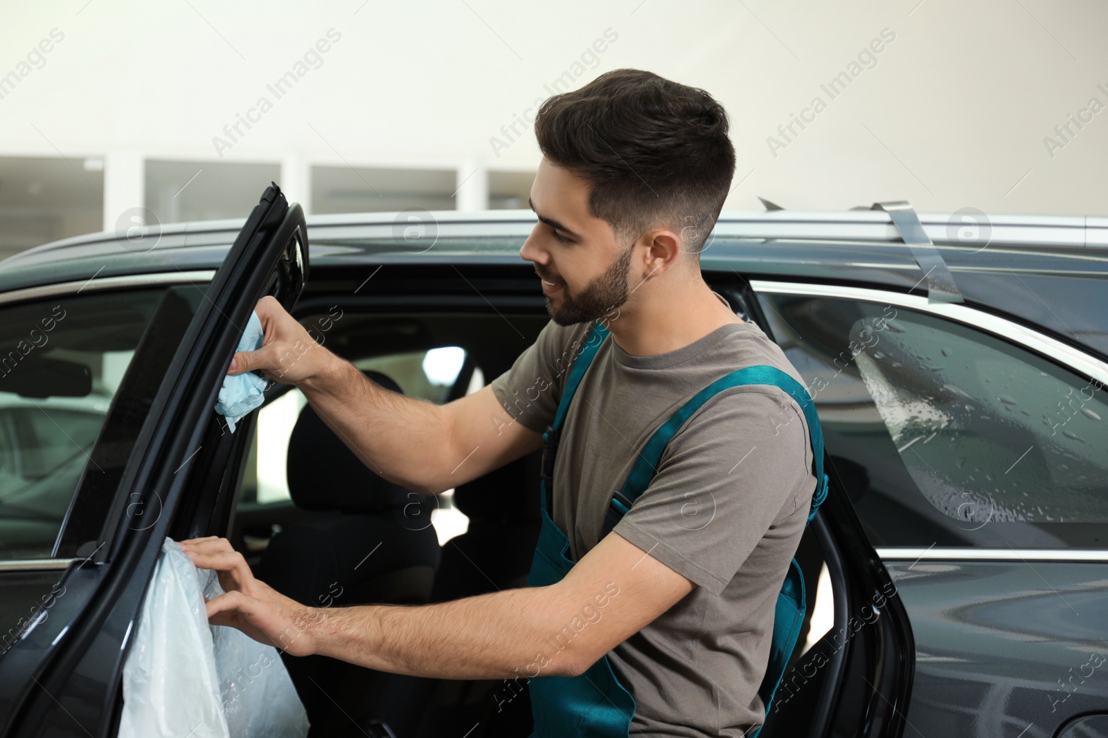 Photo of Worker washing tinted car window in workshop