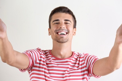 Photo of Laughing man taking selfie on white background
