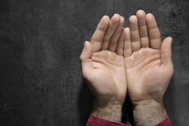 Man showing pale palms at grey table, top view with space for text. Anemia symptom