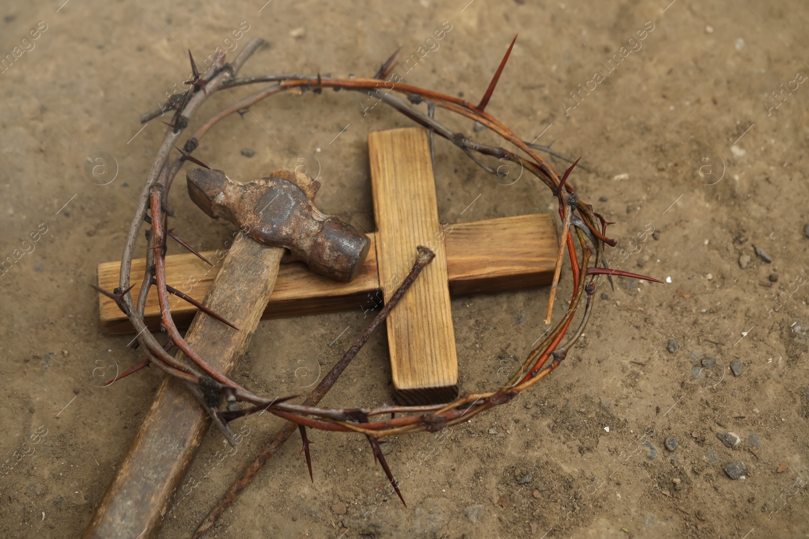 Photo of Crown of thorns, wooden cross and hammer with nail on ground, above view. Easter attributes