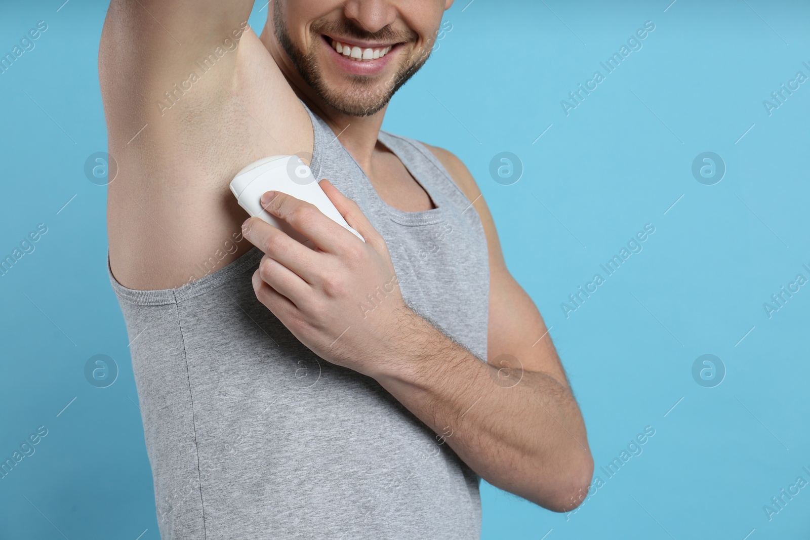 Photo of Man applying deodorant on turquoise background, closeup. Space for text