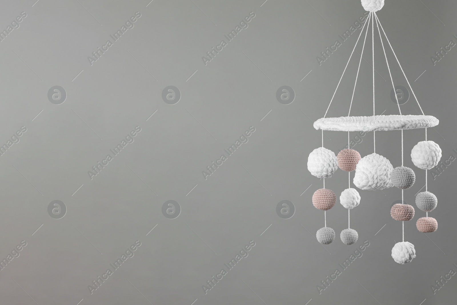 Photo of Cute baby crib mobile on grey background. Space for text