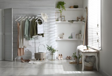 Photo of Rack with different stylish clothes, shoes and decorative elements in dressing room. Interior design