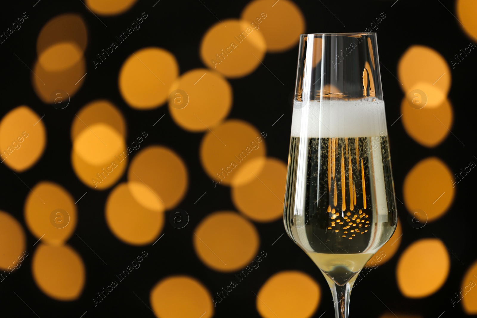 Photo of Glass of champagne against blurred lights. Space for text