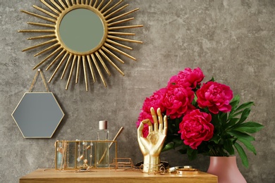 Photo of Composition with gold accessories and flowers on dressing table near grey wall