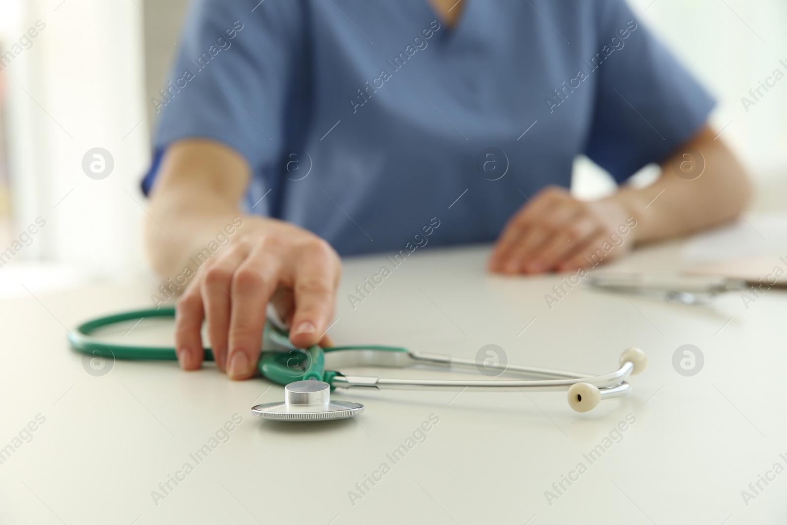 Photo of Doctor with stethoscope at white table in hospital, closeup