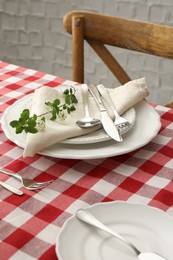 Stylish setting with cutlery, plates, napkin and floral decor on table