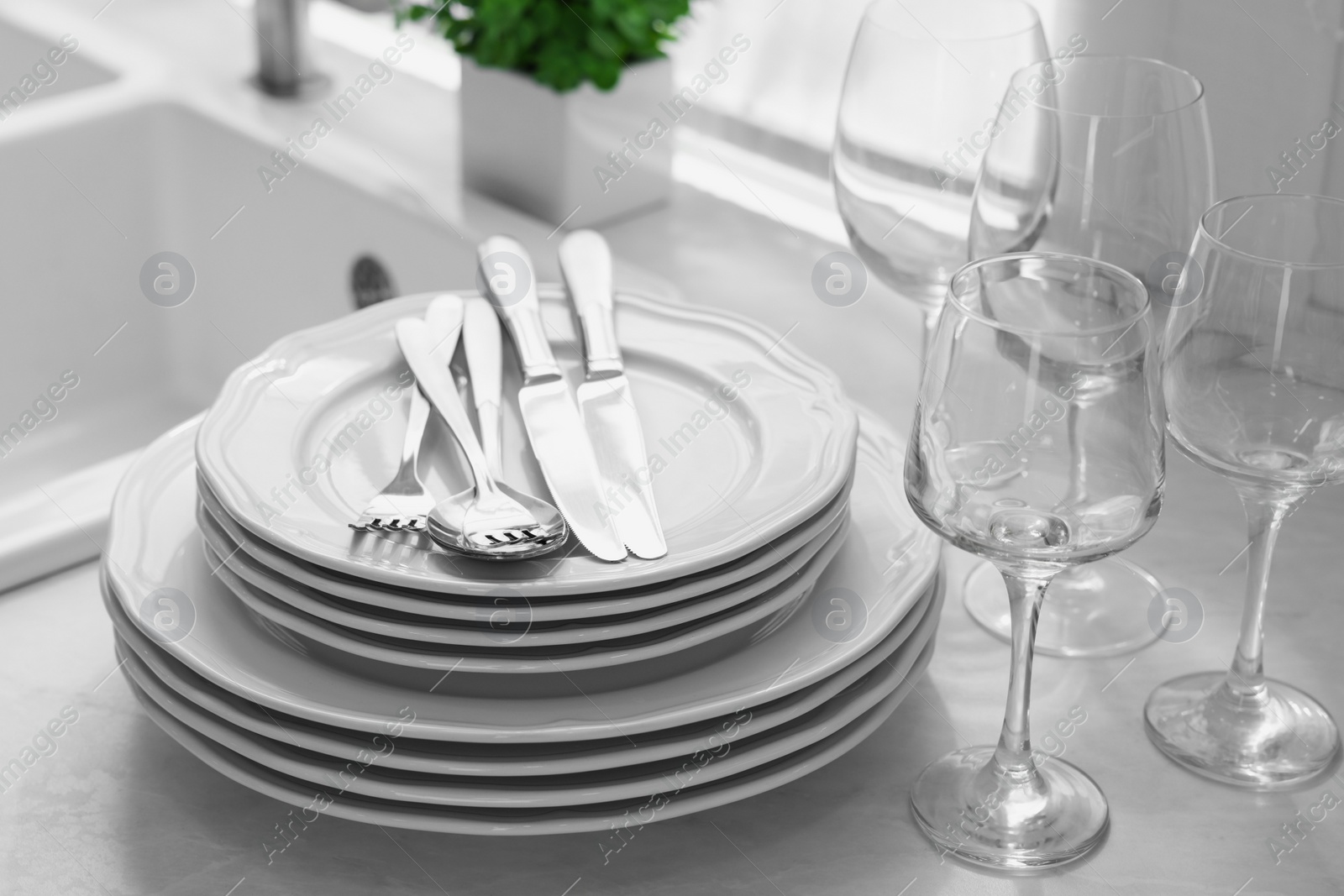 Photo of Different clean dishware, cutlery and glasses on countertop in kitchen, closeup