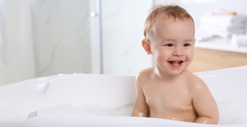 Image of Cute little baby in bathtub at home, space for text. Banner design