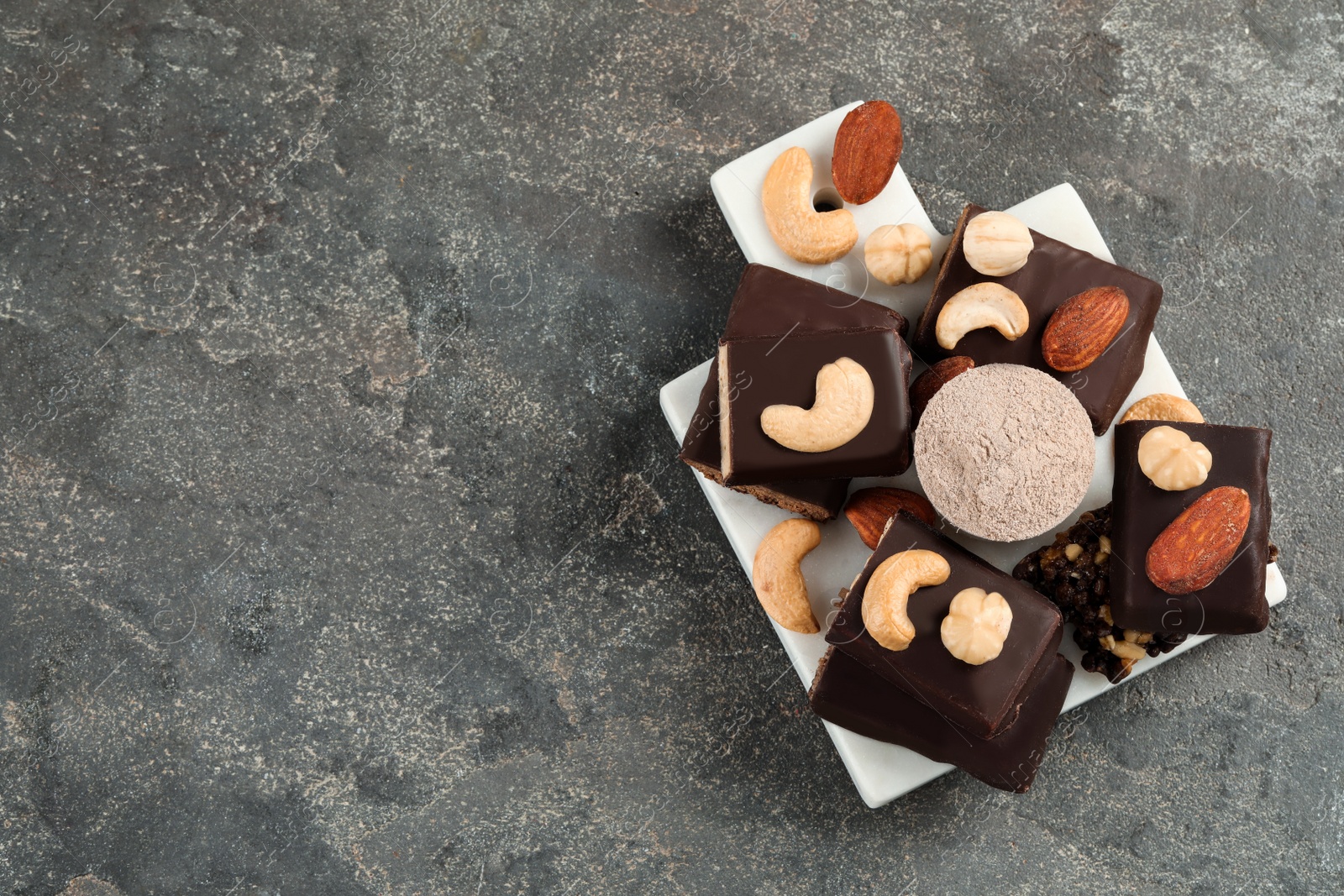 Photo of Different tasty energy bars, nuts and protein powder on grey table, top view. Space for text