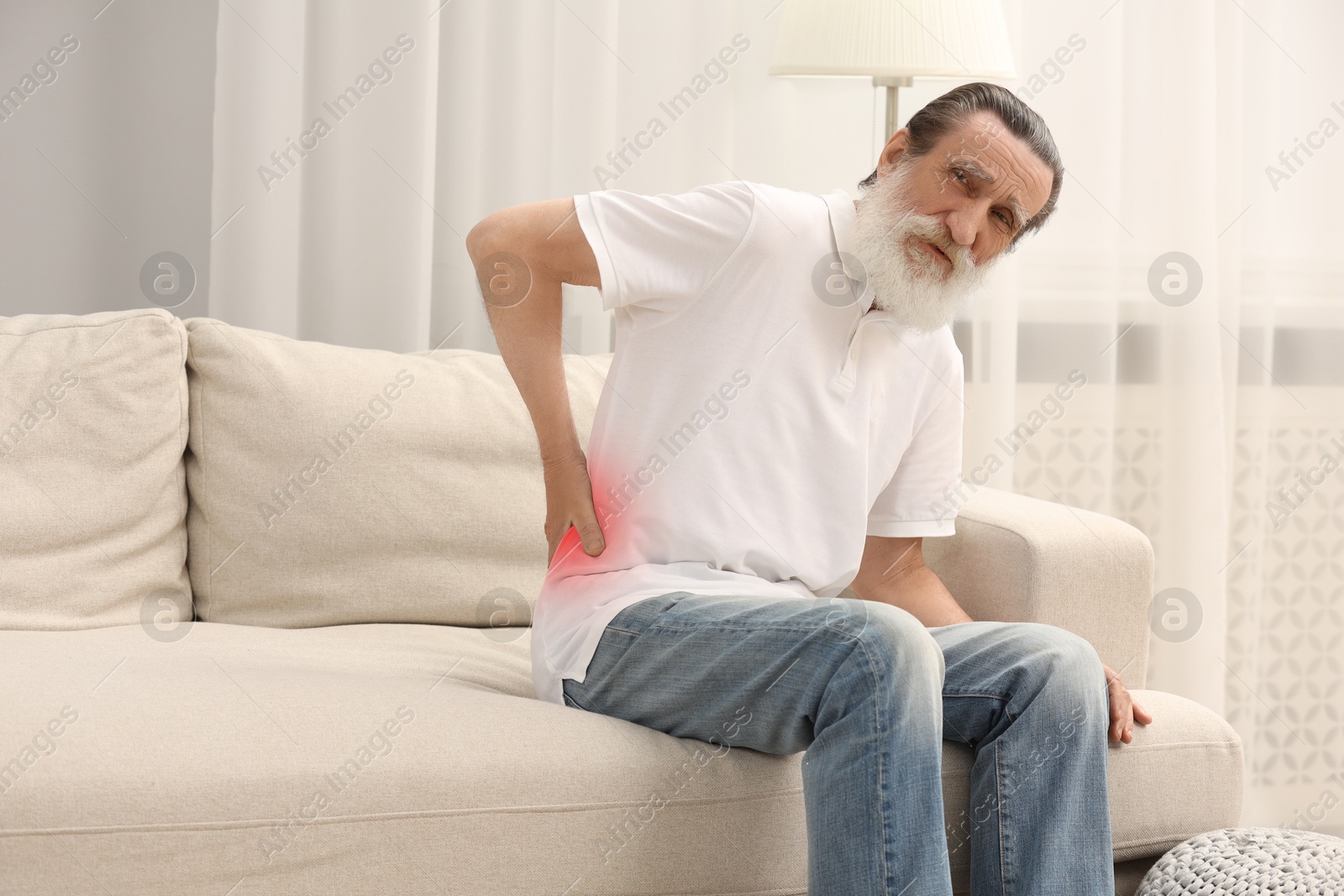 Image of Senior man suffering from back pain on sofa at home