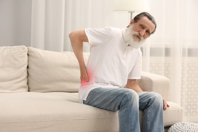 Senior man suffering from back pain on sofa at home