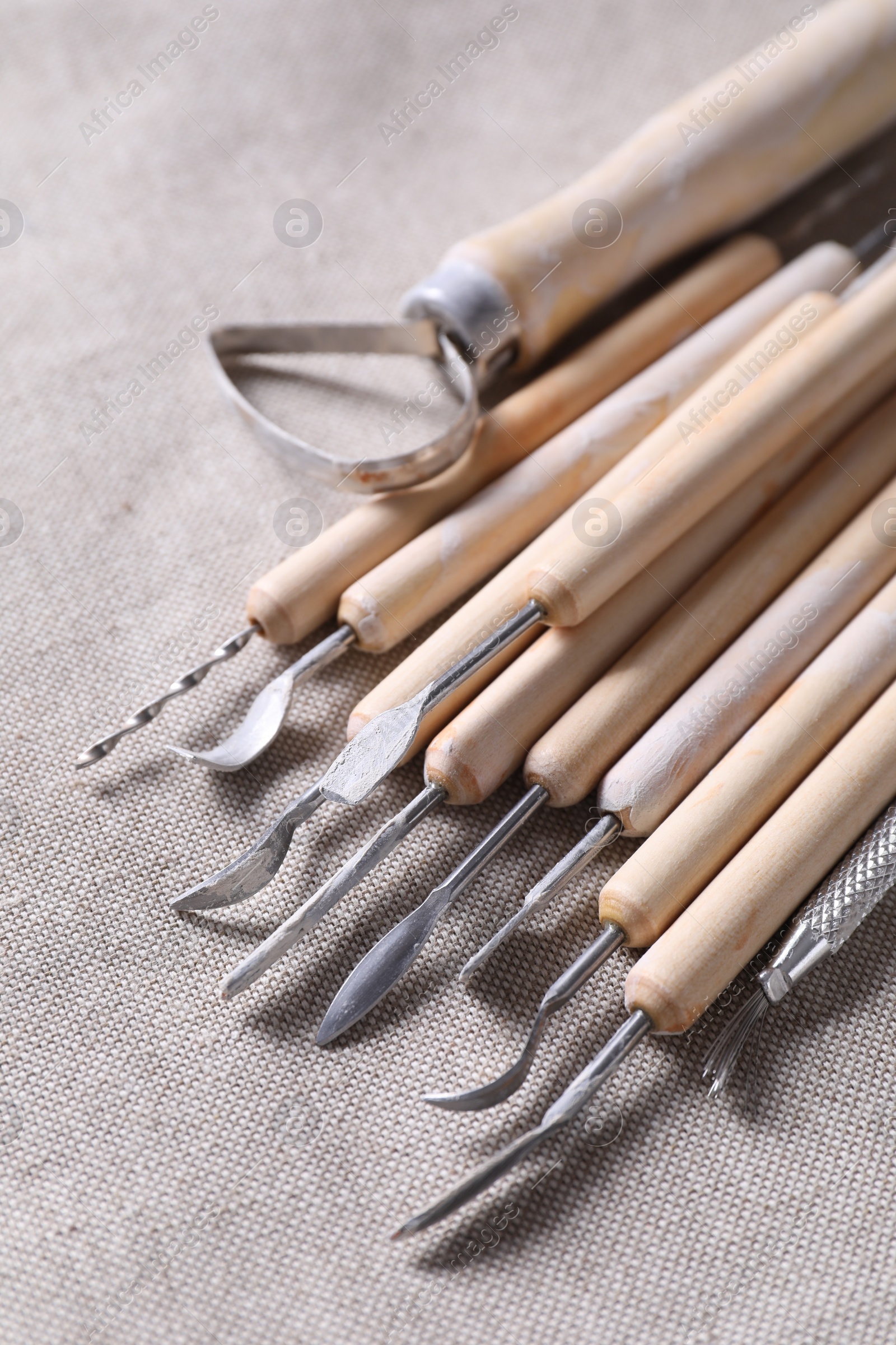 Photo of Set of different clay crafting tools on grey fabric, closeup