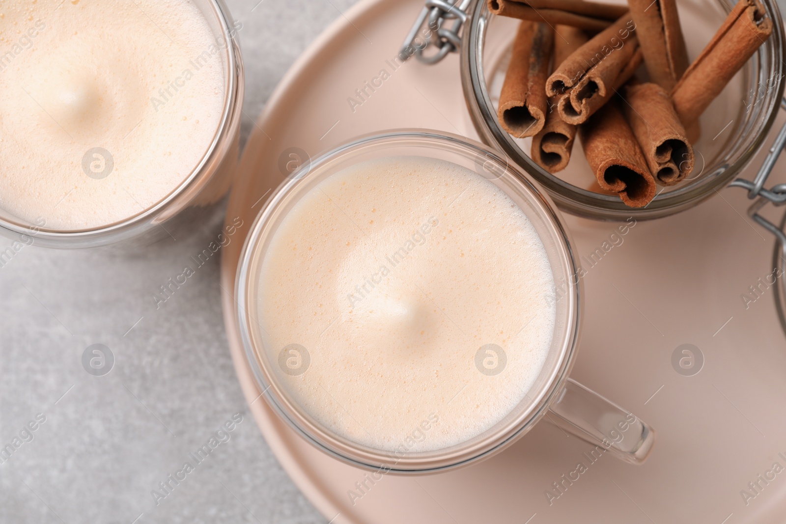 Photo of Delicious eggnog with cinnamon on light grey table, flat lay