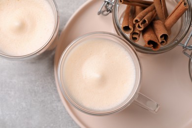 Photo of Delicious eggnog with cinnamon on light grey table, flat lay