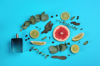 Beautiful flat lay composition with bottle of perfume, eucalyptus, tree bark and citrus fruits on blue background