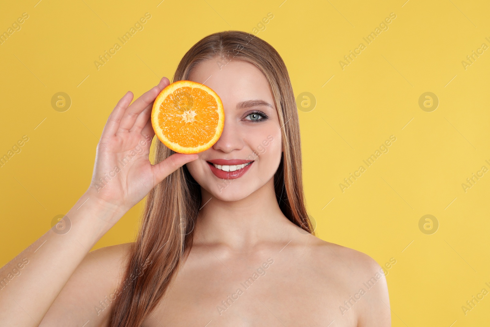 Photo of Young woman with cut orange on yellow background. Vitamin rich food