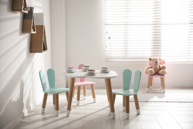 Photo of Small table and chairs with bunny ears indoors. Children's room interior