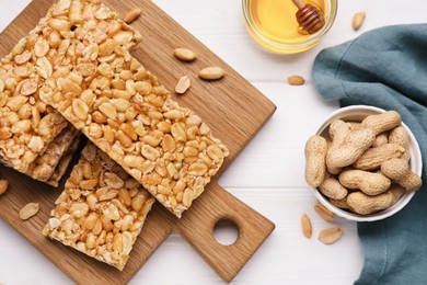 Photo of Tasty kozinaki bars, peanuts and honey on white wooden table, flat lay