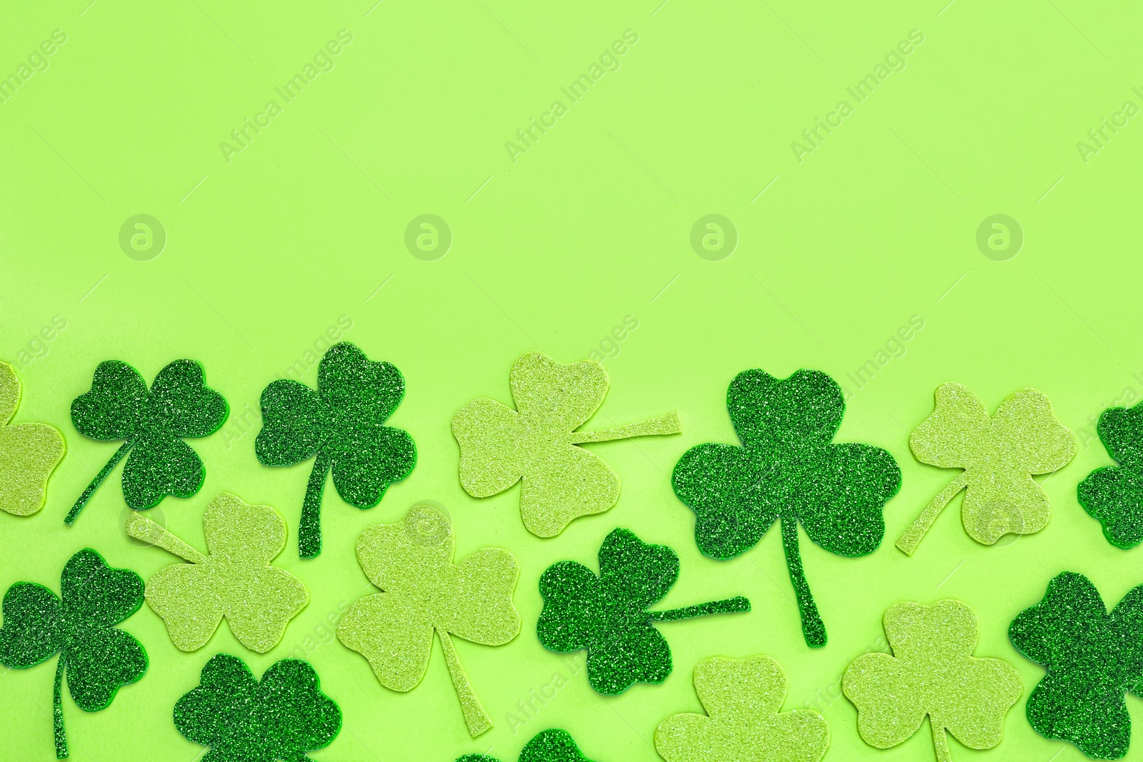 Photo of Decorative clover leaves on light green background, flat lay with space for text. Saint Patrick's Day celebration