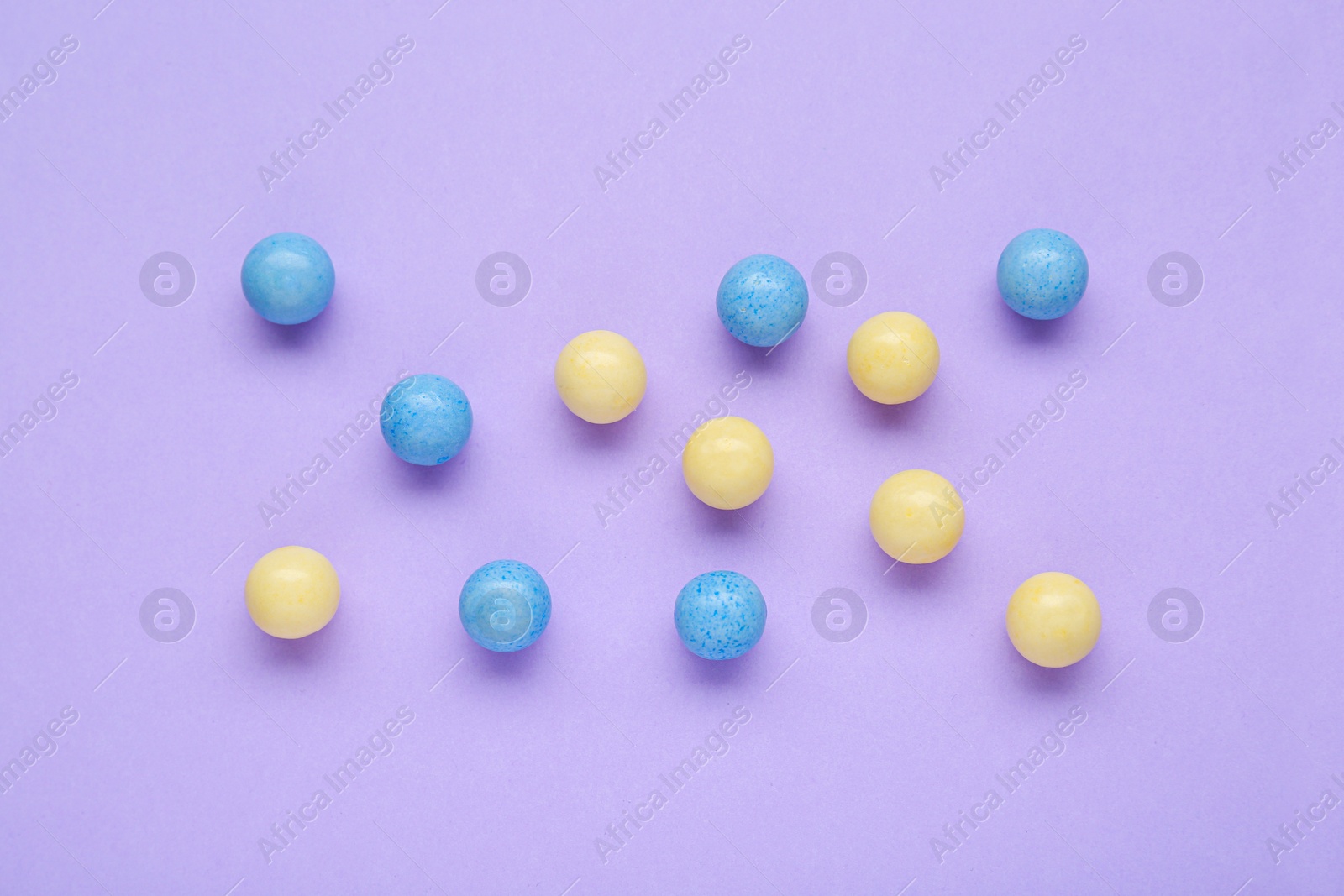 Photo of Many bright chewy gumballs on lilac background, flat lay