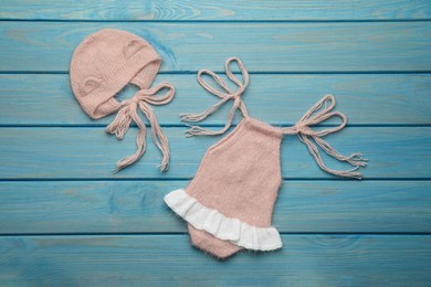 Photo of Set of cute baby knitwear for photoshoot on light blue wooden background, flat lay