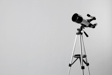 Photo of Tripod with modern telescope on light grey background. Space for text