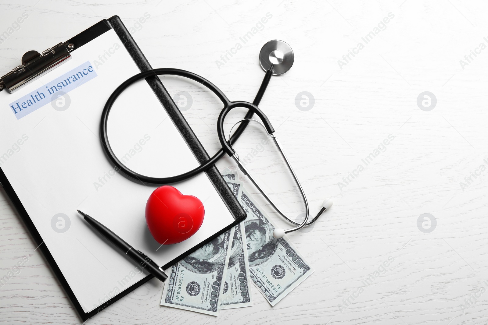 Photo of Flat lay composition with medical insurance form, money and stethoscope on white wooden table. Space for text