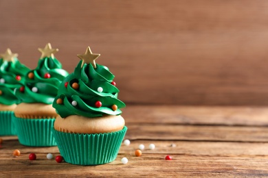 Photo of Christmas tree shaped cupcakes on wooden table. Space for text