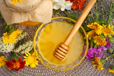Photo of Delicious honey and dipper with different flowers on wicker mat, flat lay