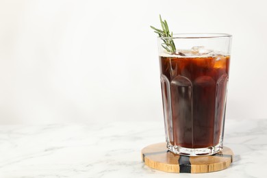 Photo of Refreshing iced coffee with rosemary in glass on white marble table, space for text