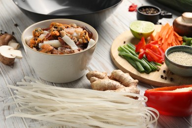 Photo of Different products and wok on light wooden table, closeup