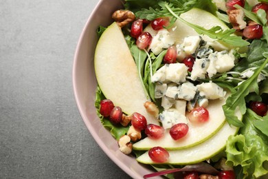 Tasty salad with pear slices and pomegranate seeds on grey table, closeup