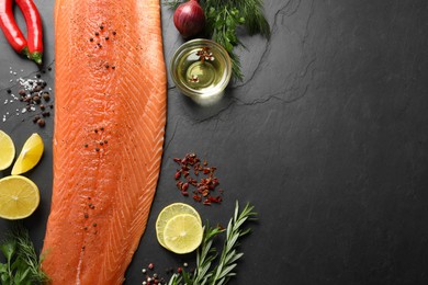 Photo of Fresh raw salmon and ingredients for marinade on black table, flat lay. Space for tex
