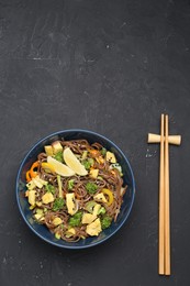 Photo of Stir-fry. Delicious cooked noodles with chicken and vegetables in bowl served on gray textured table, space for text