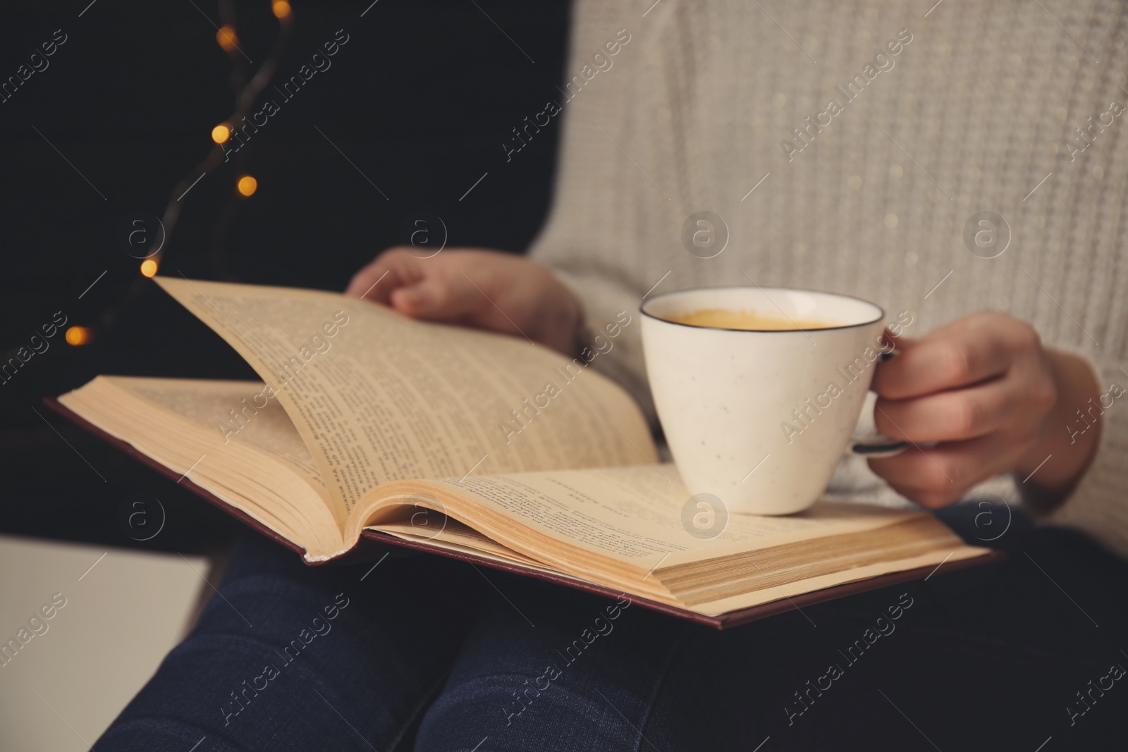 Image of Woman with cup of coffee reading book at home, closeup