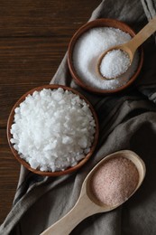 Photo of Different types of organic salt on wooden table, flat lay