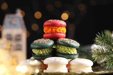 Beautifully decorated Christmas macarons and fir branches against blurred lights