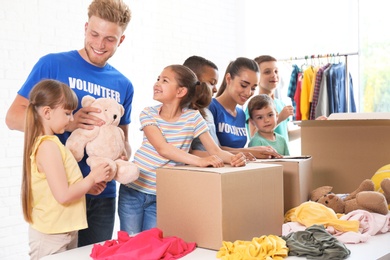 Volunteers with children sorting donation goods indoors