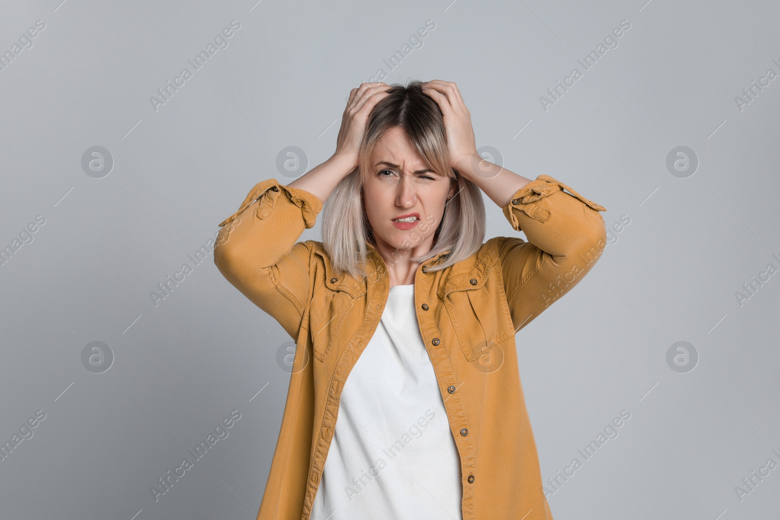 Photo of Woman suffering from headache on light grey background