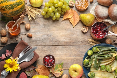 Photo of Frame made of autumn vegetables, fruits and cutlery on wooden background, flat lay with space for text. Happy Thanksgiving day