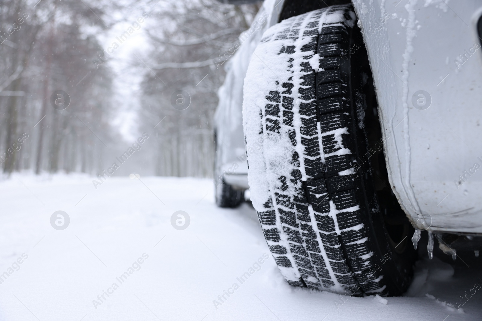 Photo of Car with winter tires on snowy road outdoors, closeup. Space for text