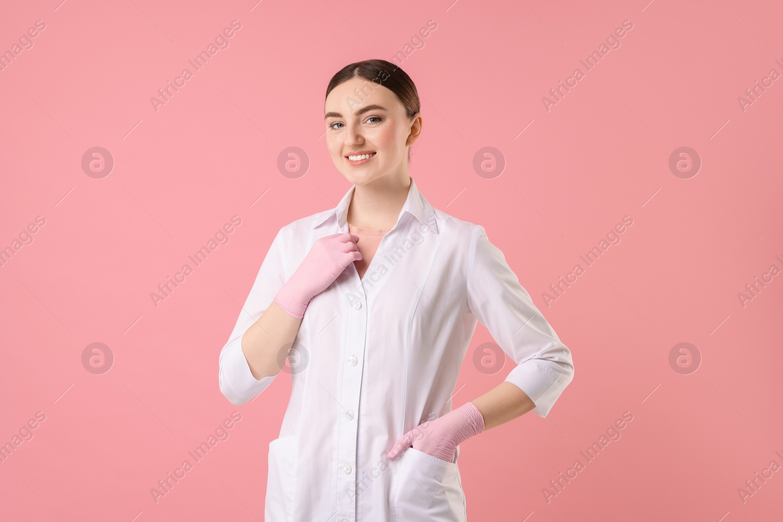 Photo of Cosmetologist in medical uniform on pink background