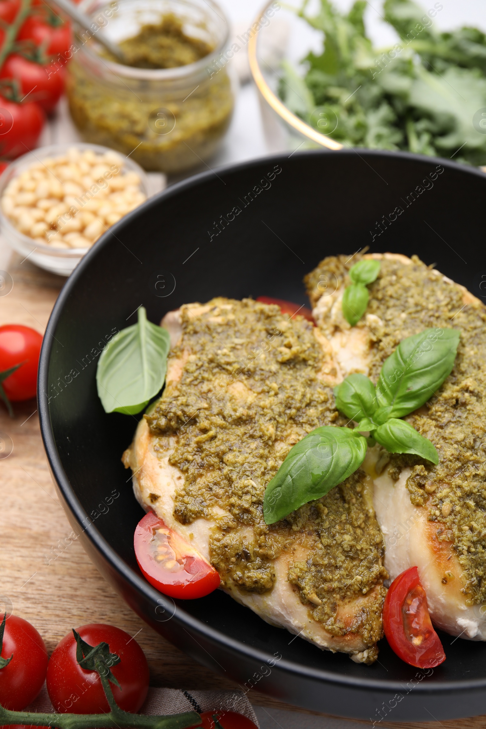 Photo of Delicious chicken breasts with pesto sauce, tomatoes and basil on table, closeup